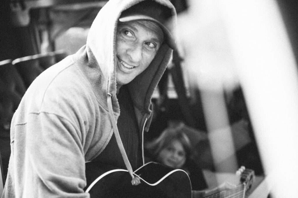 Dan Bern wearing a hoody and playing guitar